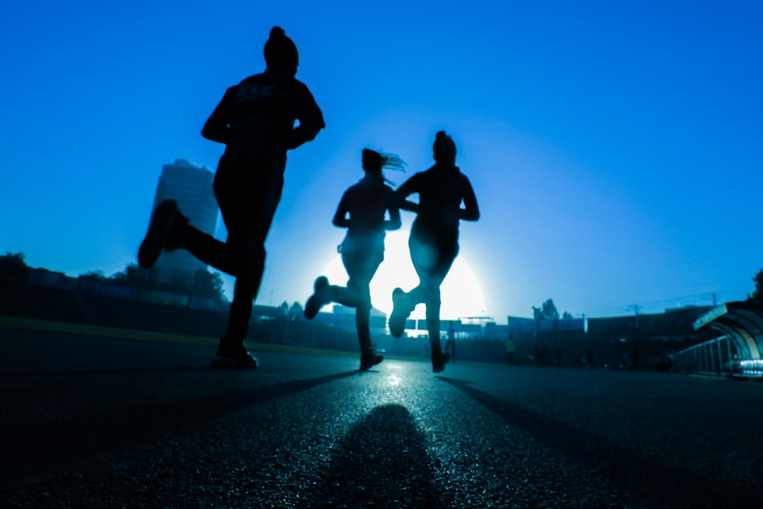 silhouette-of-three-women-running-on-grey-concrete-road-ogv9xil7dky